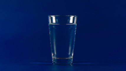Full glass with clear water on a blue background