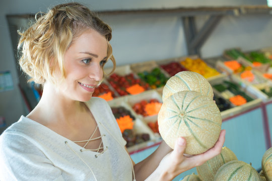 beautiful woman choosing ripe organic melon