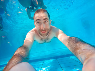 Young handsome man diving underwater in a swimming pool