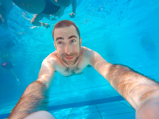 Young handsome man diving underwater in a swimming pool
