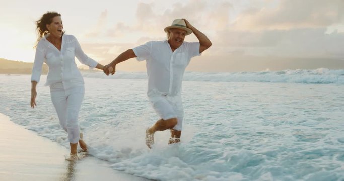 Romantic middle age retired couple enjoying sunset walk on vacation