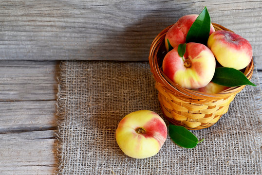 Chinese flat donut peaches in the basket on old wooden table also known as Saturn donut, Doughnut peach, Paraguayo.Healthy eating or diet concept.Selective focus.