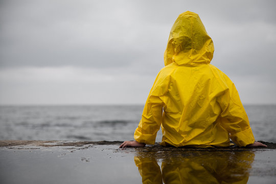 Rainy clouds. Child in a yellow raincoat.