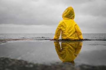 Rainy clouds. Child in a yellow raincoat. © Denys