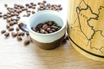 Coffee beans with cup and keg on wooden table