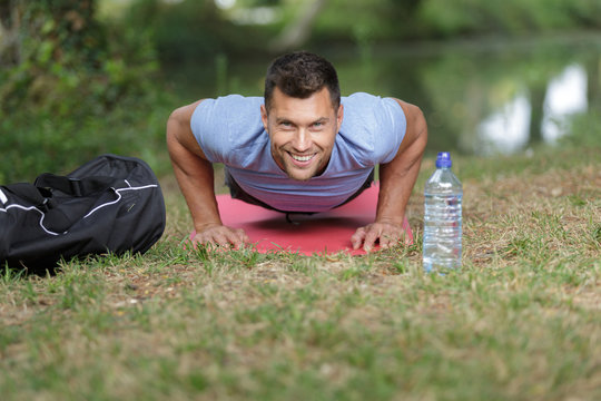 happy man doing push upson grass in summer