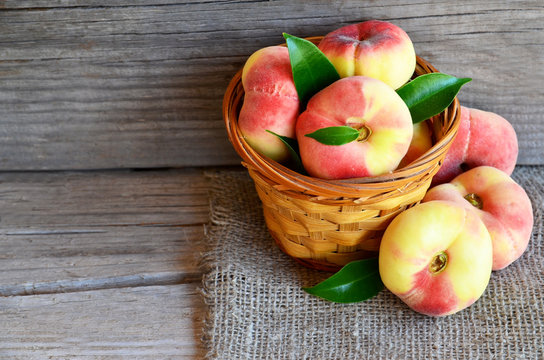 Chinese flat donut peaches in the basket on old wooden table also known as Saturn donut, Doughnut peach, Paraguayo.Healthy eating or diet concept.Selective focus.