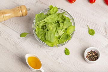 Fresh spinach leaves, tomatoes and other salad ingredients on a light background