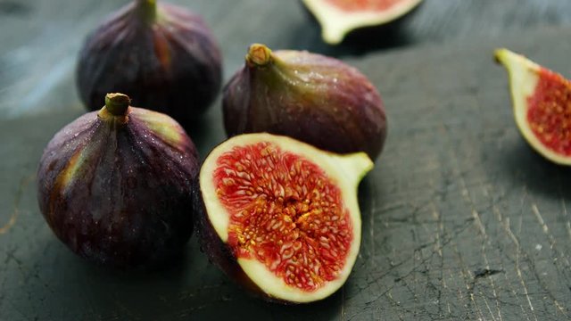 Arrangement of whole and cut fresh ripe figs with soft juicy flesh composed on rough wooden table