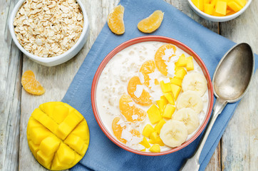 Oatmeal with mango, banana, tangerine oranges and coconut flakes