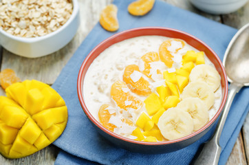 Oatmeal with mango, banana, tangerine oranges and coconut flakes