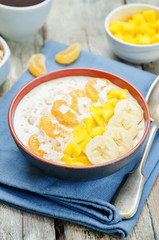 Oatmeal with mango, banana, tangerine oranges and coconut flakes