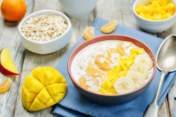 Oatmeal with mango, banana, tangerine oranges and coconut flakes
