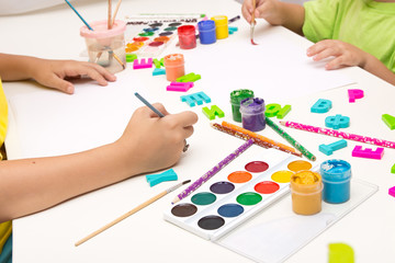 Children paint with gouache, paints , pencils. Mobile and entertainment Board games for children.Ceramic dishes in working process. Creating color patterns