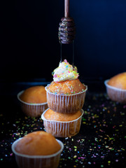 Сupcakes with sprinkling and honey on a dark background.