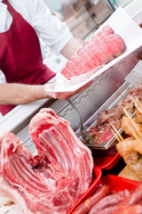 Butcher adding joint of beef to display