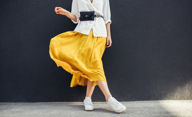 Horizontal cropped image of stylish slim woman in beautiful yellow skirt. Caucasian female fashion...