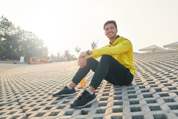 Fototapeta na wymiar Athletic Man With Fit Body In Yellow Sportswear Resting on Gray
