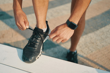 Sportsman ties his black sneakers