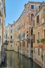 Fototapeta na wymiar Venice canal with ancient buildings and houses facades in a sunny day in Italy