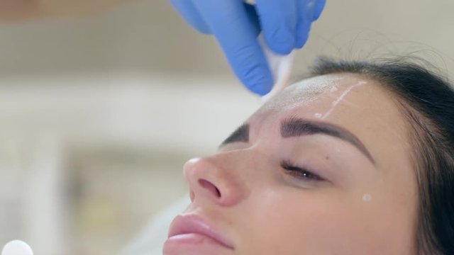 beauty clinic, hands of cosmetologist making botox injection in face of young woman closeup