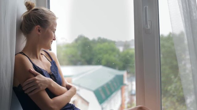 Girl sits by the window and smiles