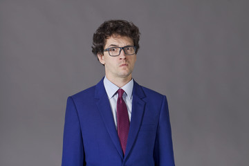 Young boy with glasses and blue suit grimacing