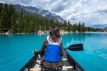 Female tourist canoeing on Moraine Lake in Banff National Park, Canadian Rockies, Alberta, Canada.