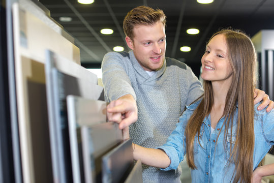 young happy couple looking at bathroom tile in furniture store