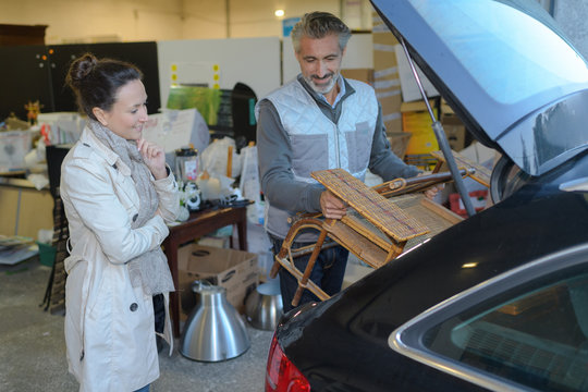 man helps customer to put furniture in her car