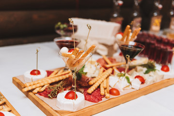Close up of a variety of bread sticks, cold cuts and cheeses, including salami, ham, brie and camembert served to guests buffet style as appetizers at a wedding reception or event