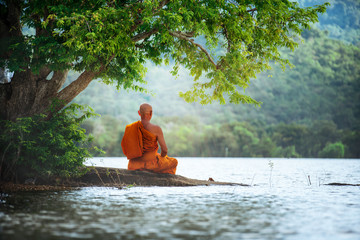 Boeddhistische monnik in meditatie naast de rivier met prachtige natuurachtergrond