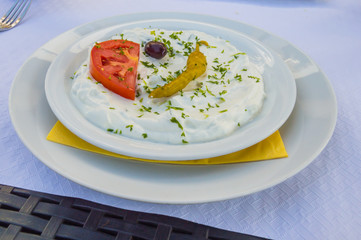 Plate of tzatziki with a tomato and an olive in a restaurant of Florenville