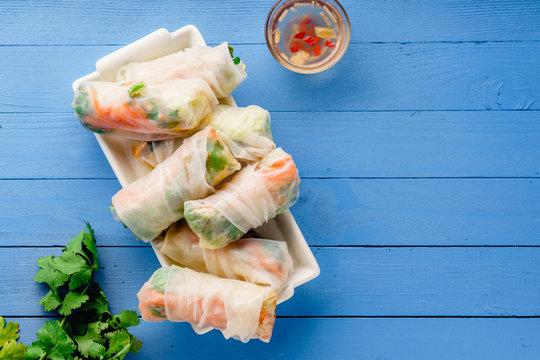 Vegetarian spring rolls with tofu, marinated carrot and daikon and cilantro on blue painted wooden table