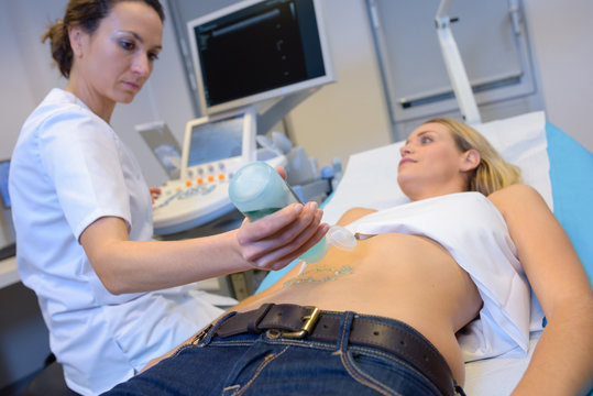 Nurse applying jelly to patient's abdomen for ultrasound