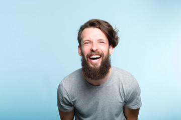 happiness enjoyment and laugh. man with a wide grin. portrait of a young bearded hipster guy on...