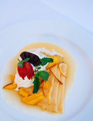 Crepe or pancake with ice cream, strawberry and sweet orange sauce