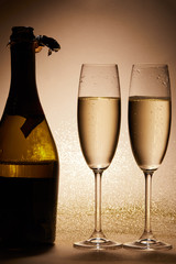glasses and bottle of champagne with glitter on tabletop, christmas concept