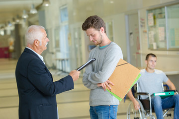 teacher reprimanding young student in school corridor