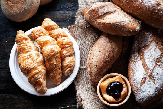 The Croissant tray put beside Baguette gread and blueberry pie,on wooden desk