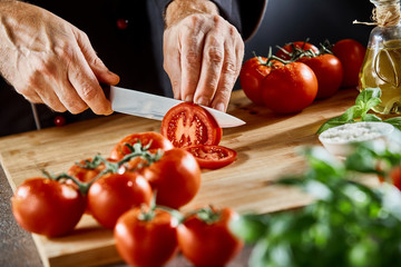 Close up on man slicing up small tomatoes - Powered by Adobe