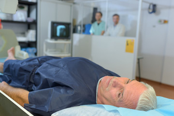 Obraz premium Patient having xray, medical staff shielded behind partition
