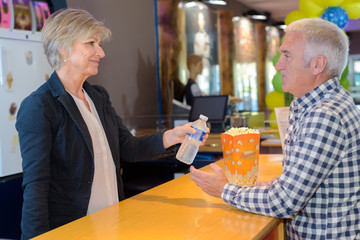 Lady serving man popcorn and water