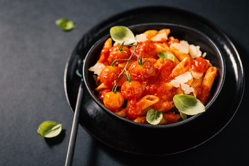 Tasty tomato pasta in bowl on dark