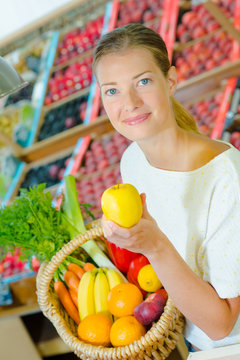 Woman holding a basket full of different fruit