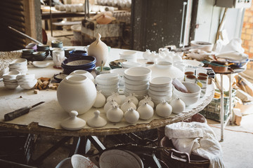 The full table of white unpainted unfinished traditional greek handcrafted ceramics inside the ceramic workshop of ceramic craft in Greece