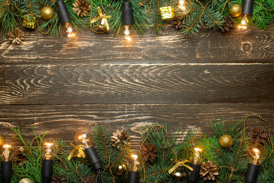 Christmas rustic background - old wooden board with backlight and branches of a Christmas tree and shyshkami and a free text space