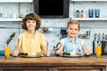 adorable kids eating vegetables and smiling at camera in kitchen