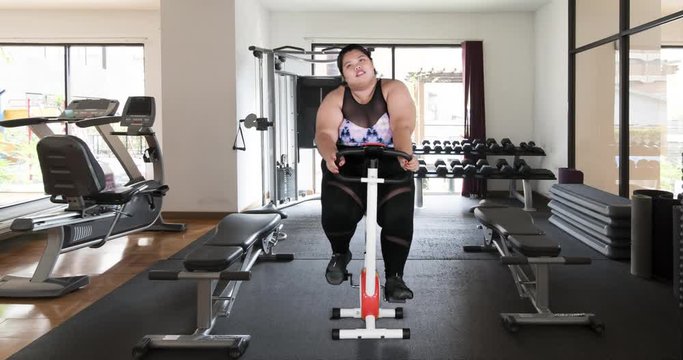 Exhausted overweight woman riding exercise bike in gym. Shot in 4k resolution