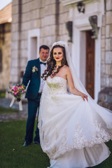 Naklejka premium Wedding day. Beautiful fairytale newlywed couple hugging near old medieval castle. Sensual married couple bride and groom valentines hugging in front of old castle wall.
